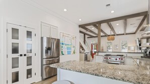 A modern kitchen with granite countertops, stainless steel appliances, and a central island with bar stools. - Bikes | Pool | Ping Pong | Beach Service (Santa Rosa Beach)
