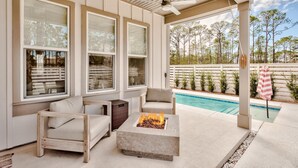 Un patio couvert avec une piscine, du mobilier d’extérieur et un foyer.
