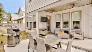 Un patio couvert avec un barbecue, des sièges d’extérieur et un foyer.