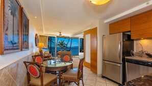 Una cocina moderna con refrigerador de acero inoxidable, armarios de madera y una zona de comedor con sillas de mimbre y una mesa de vidrio.