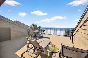 A patio with a table, chairs, and a small round table with drinks.