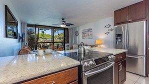 A modern kitchen with a large island, stainless steel appliances, and a view of the outdoors. - Maui Vista 2213 Kihei condo across Charley Young Beach, summer deal (Kihei)