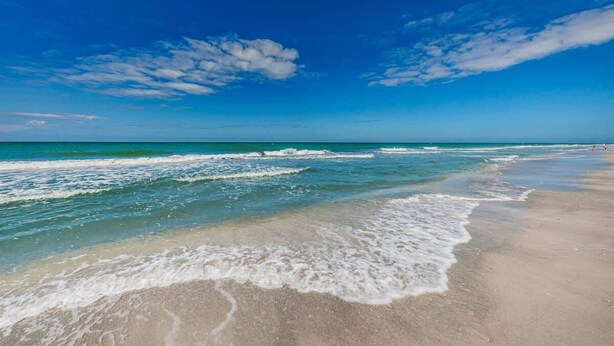 Una playa con cielos despejados y olas.