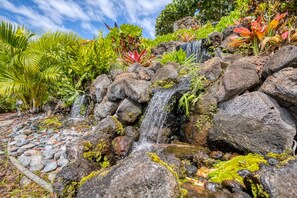 A garden with a small waterfall, rocks, and various plants.