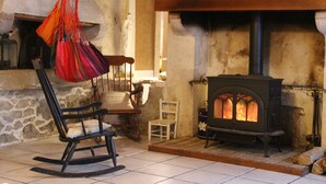 A cozy room with a stone fireplace, a rocking chair, and a hanging chair.