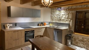 A modern kitchen with wooden cabinets, a built-in oven, a sink, and a stone accent wall.