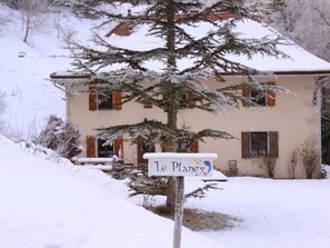 Ein schneebedecktes Haus mit einem Schild, auf dem 'Le Planey' steht.