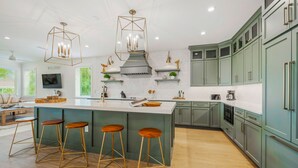 Una cocina moderna con una isla central, taburetes de bar y armarios verdes.