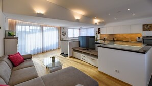 Una sala de estar moderna con un sofá, una mesa de centro de vidrio y un televisor.