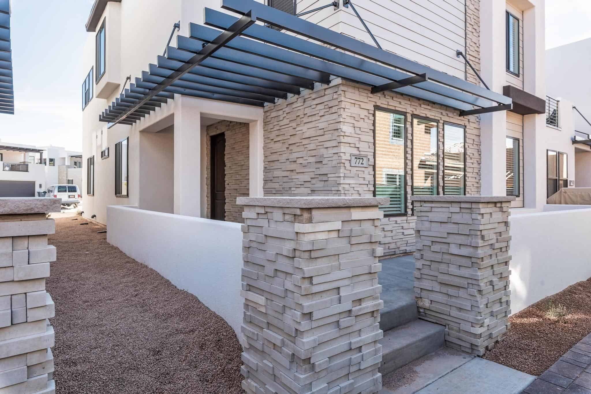 A modern building with a stone facade, a covered entrance, and a visible address number.