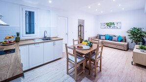 A modern kitchen with white cabinets, a wooden dining table, and a built-in oven.