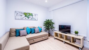 A modern living room with a sectional sofa, a flat-screen TV, and a wooden entertainment unit.