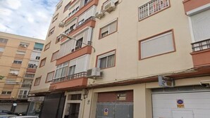 A multi-story residential building with balconies, air conditioning units, and a garage door.