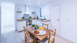 A modern kitchen with white cabinetry, a wooden dining table, and a breakfast setting.