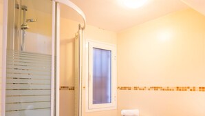 Un baño con cabina de ducha de vidrio, inodoro y lavamanos.