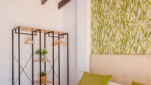Un dormitorio con cama, armario empotrado con estantes y un llamativo papel pintado botánico.