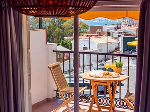 A balcony with a wooden table, two chairs, and a view of the cityscape.