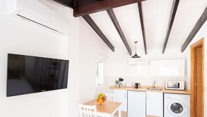 Una cocina moderna con armarios blancos, microondas, lavadora y comedor con mesa y sillas.