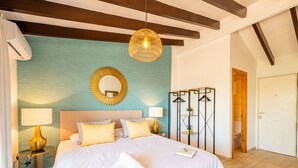 A bedroom with a large bed, two bedside lamps, a mirror, and a hanging light fixture.