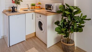 A compact kitchen with a washing machine, a microwave, and a sink.