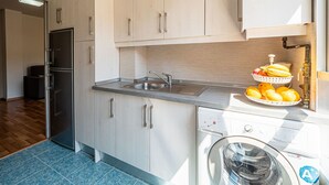 A modern kitchen with light-colored cabinets, a stainless steel sink, and a built-in washing machine. - Sunset Malaga Apartments - Maestranza 8d2 (Málaga)