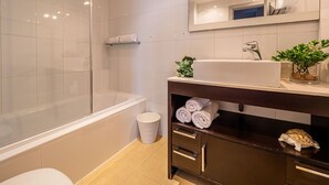 A modern bathroom with a glass shower enclosure, a white bathtub, a vanity with a sink, and a mirror above the vanity. - Sunset Malaga Apartments - Maestranza 8d2 (Málaga)