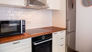 A modern kitchen with white cabinets, a built-in microwave, an oven, and a stainless steel refrigerator.