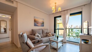 A modern living room with a sofa, armchairs, a coffee table, and a balcony with a city view. - Sunset Malaga Apartments - PALM BEACH (Torremolinos)