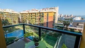 A balcony with a view of a swimming pool, a tennis court, and surrounding buildings. - Sunset Malaga Apartments - PALM BEACH (Torremolinos)