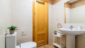 Ein kleines Badezimmer mit Toilette, Waschbecken, Spiegel und Holztür.
