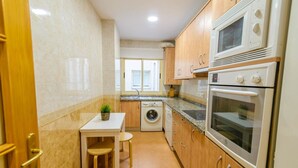 Eine kleine Küche mit Waschmaschine, Mikrowelle und Backofen.