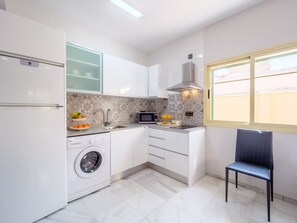 Une cuisine compacte équipée d’un lave-linge, d’un four à micro-ondes et d’un évier.