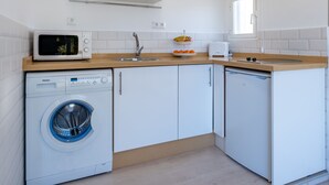 A compact kitchen with a microwave, toaster, sink, and dishwasher.