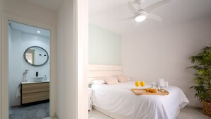 A modern bedroom with a bed, bedside table, and a ceiling fan. - Sunset Malaga Apartments - Blaser 2E (Málaga)