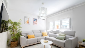 A modern living room with a grey sectional sofa, a small white coffee table, and a large potted plant. - Sunset Malaga Apartments - Blaser 2E (Málaga)