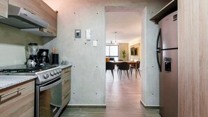 Een moderne keuken met een gasfornuis, oven en een ingebouwde magnetron. Achtergrond toont een eethoek met een tafel en stoelen.