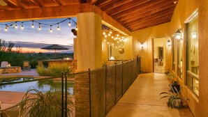 Un espacio al aire libre cubierto con piscina, luces colgantes y techo de madera.