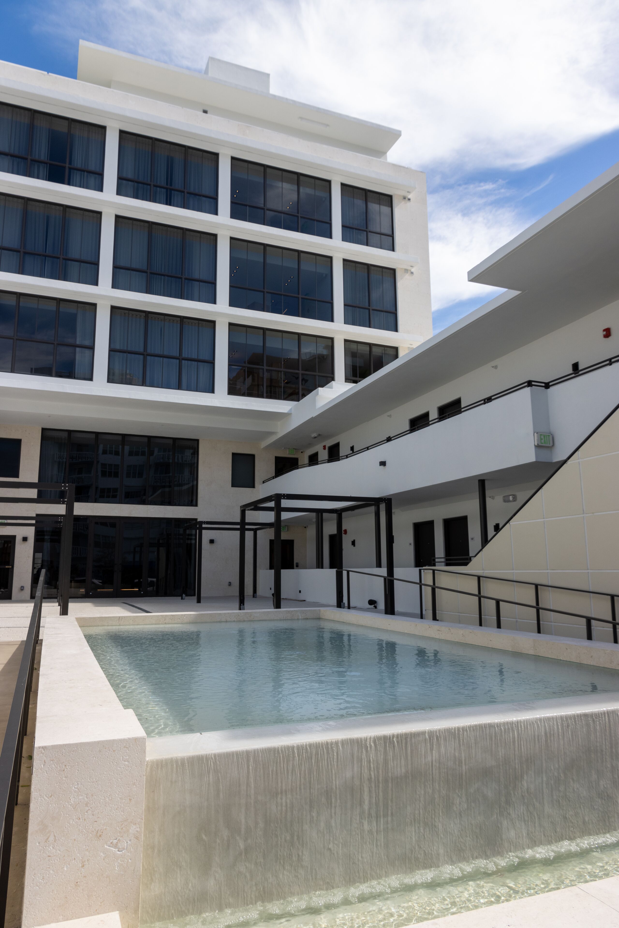 Un bâtiment moderne doté d’une piscine, de grandes fenêtres et d’un escalier.