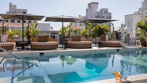 A pool area with lounge chairs and umbrellas, surrounded by buildings. - UMA House by Yurbban South Beach (Miami Beach)