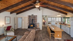 A spacious living area with a fireplace, a kitchen with modern appliances, and a loft ceiling.