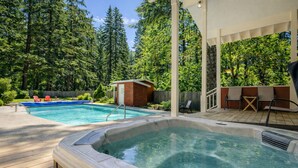 A backyard with a hot tub, a swimming pool, and a covered patio area.