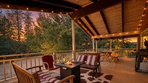 An outdoor deck with wooden furniture, a fire pit, and string lights.