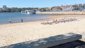 A beach with a concrete bench, a row of sun loungers, and a boat in the water. - CASA MIRA DOURO marina beach 5mnts on foot caves, Porto bridge 5mnts by car (Vila Nova de Gaia)