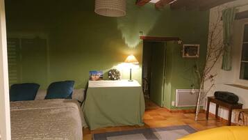 Une pièce avec un lit, une table avec une lampe, un petit sapin de Noël et un radiateur.