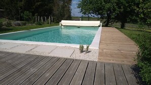 Una piscina rectangular con un muelle de madera alrededor.