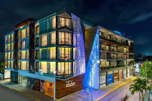 A modern hotel with multiple floors, balconies, and a distinctive illuminated facade.