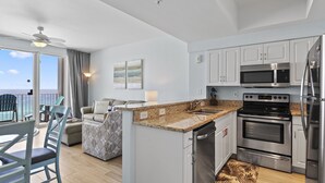 A modern kitchen with stainless steel appliances, a granite countertop, and a view to the ocean. - Majestic Sun 807A - Panoramic Gulf Views, Indoor/Outdoor Pool, Hot Tub, Fitness! (Miramar Beach)
