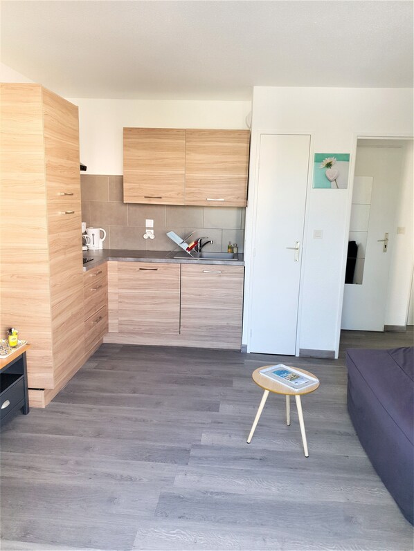 Una cocina moderna con armarios de madera, un lavabo y una pequeña mesa con una revista.