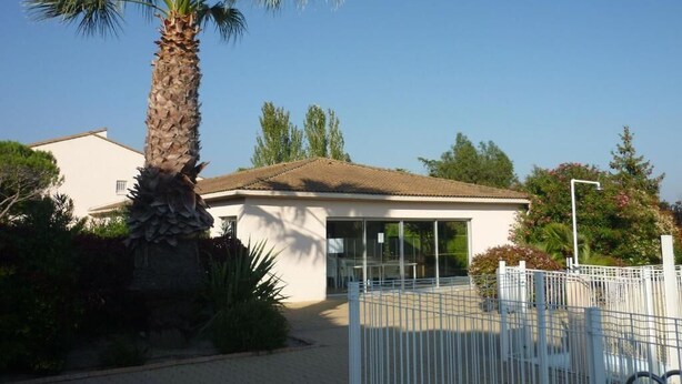 A building with a tiled roof, a palm tree, and a fenced area. - Les Jardins Du Golf - Mandelieu (Mandelieu-La-Napoule)