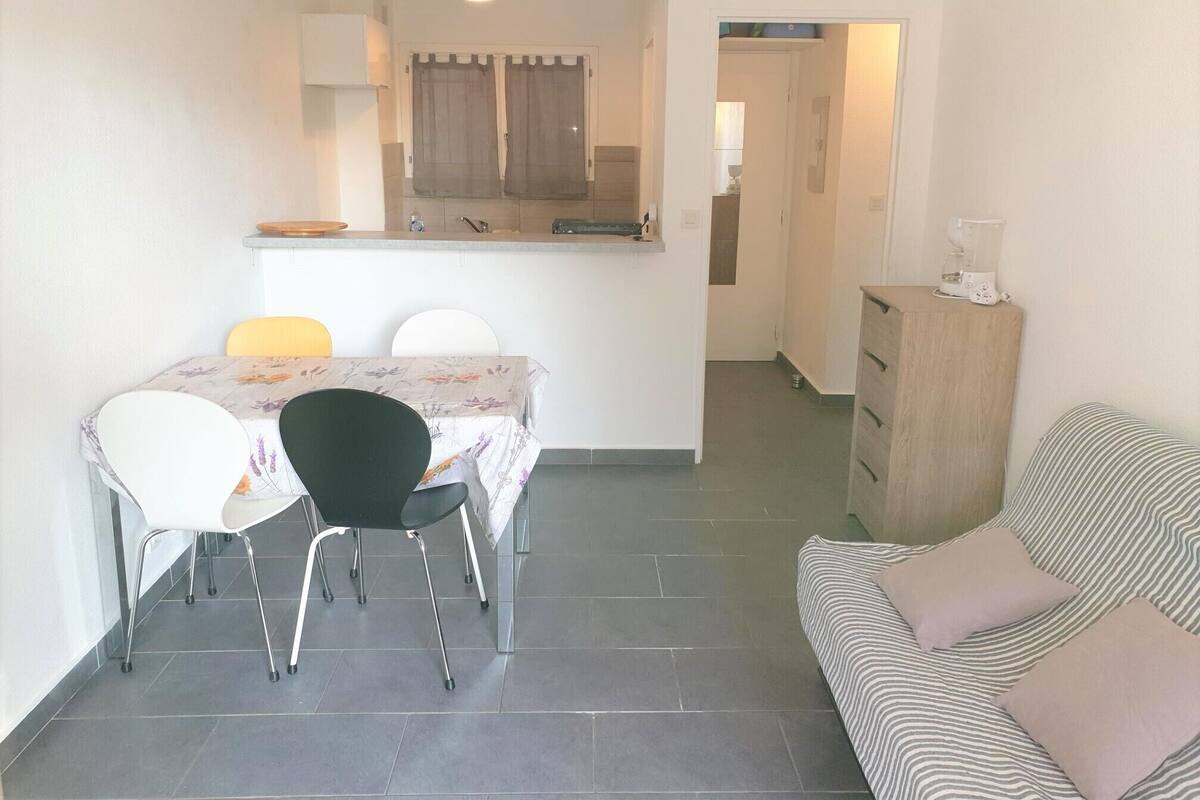 A compact living space with a dining area, kitchenette, and a sofa.